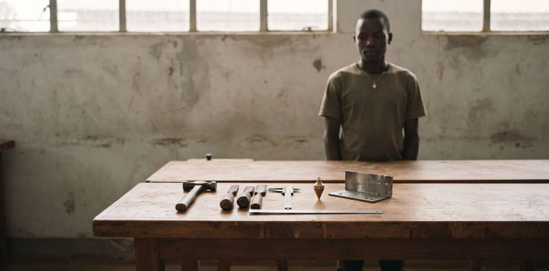 Hand tools laid out on a workbench in a workshop, a student standing behind it